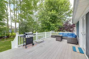 Une terrasse couverte avec un barbecue, du mobilier d’extérieur et une rambarde blanche.