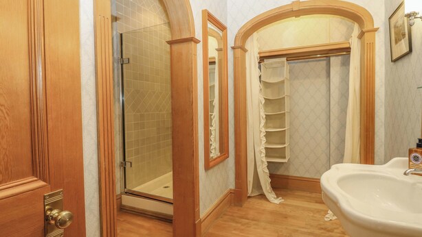 A bathroom with a wooden door, a glass shower enclosure, a vanity with a sink, and a towel rack. - Creag Bhalg (Ballater)