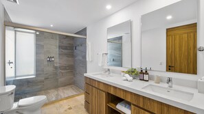 Un baño moderno con cabina de ducha de vidrio, tocador de madera y un espejo grande.
