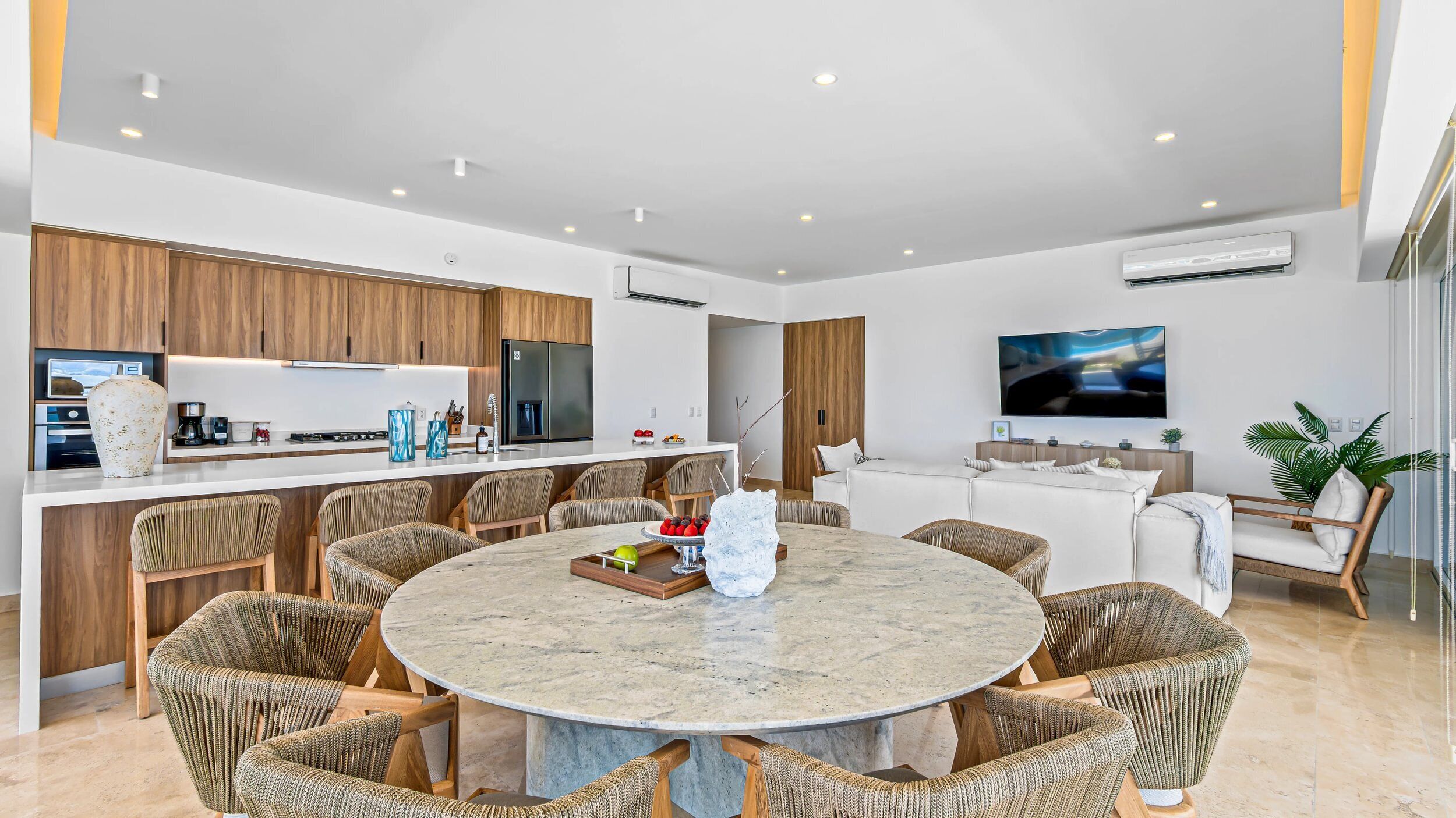 Une cuisine moderne avec des meubles en bois, un îlot central et un coin repas doté de chaises en osier.