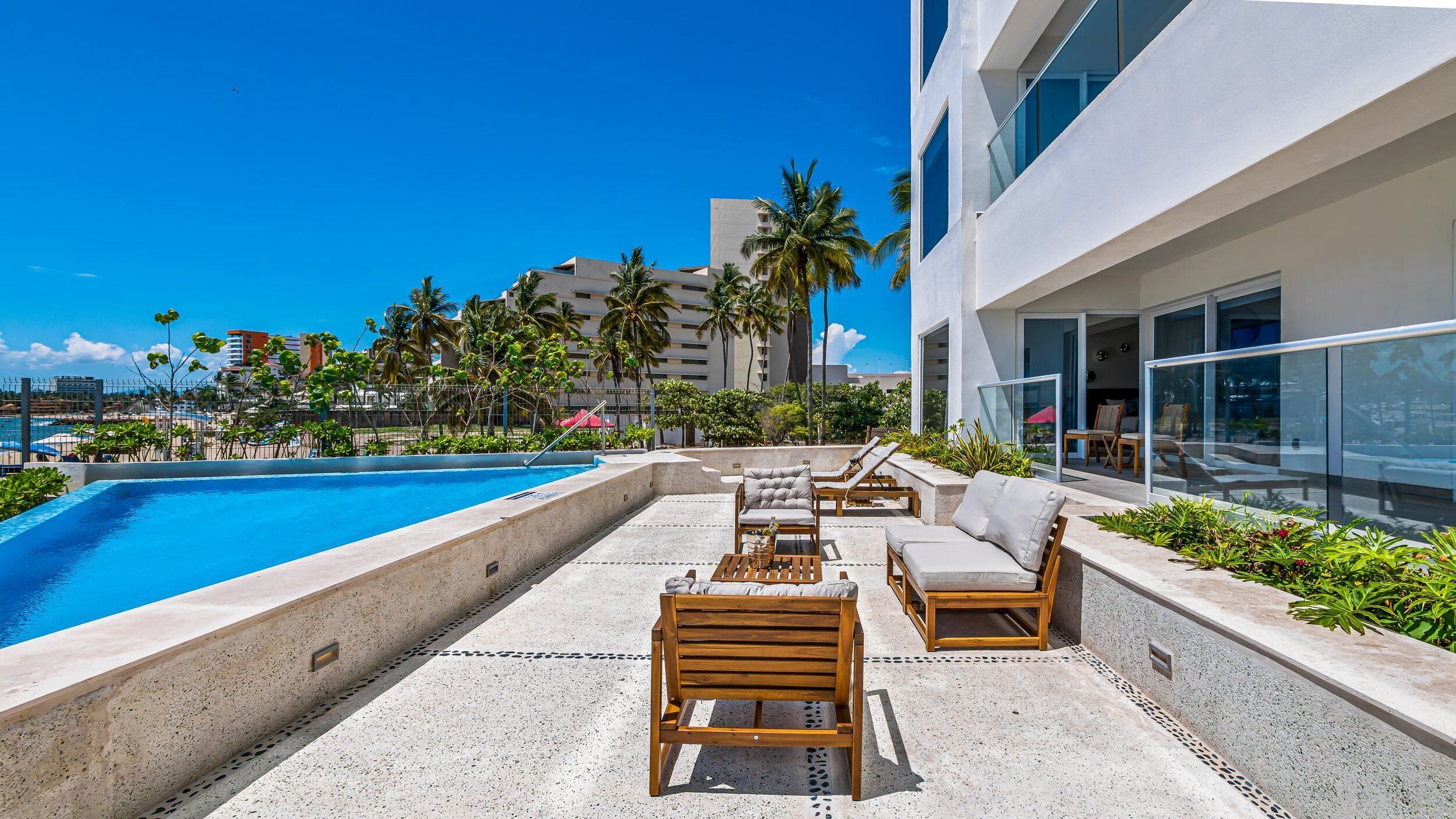 A poolside area with lounge chairs and a clear view of the ocean.