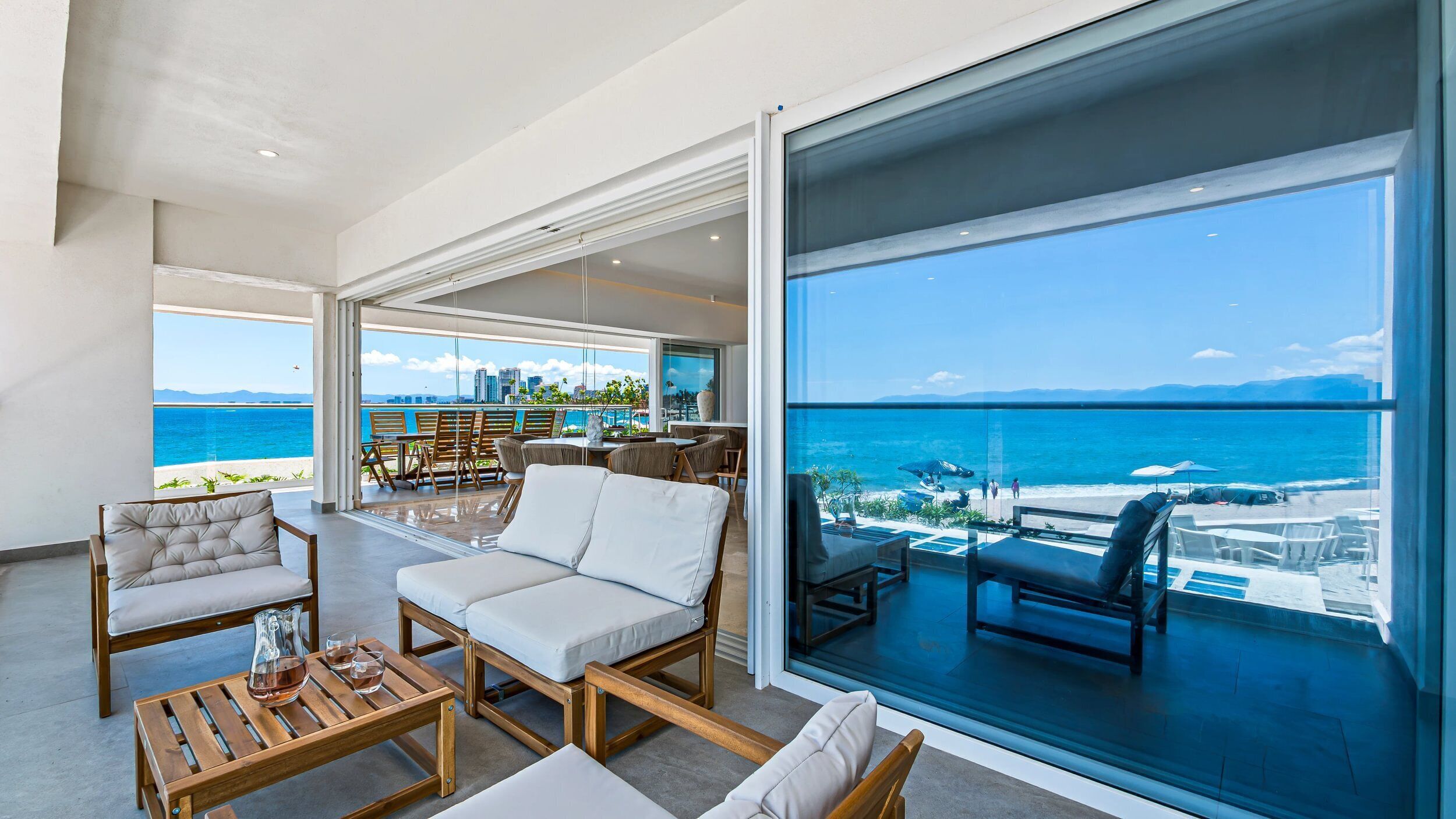 A spacious living area with a large balcony overlooking a beach and ocean.