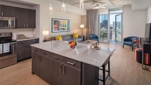 A modern kitchen with dark wood cabinets, a stainless steel microwave, and a granite countertop. - 1BD Suite in Downtown Austin! (Austin)