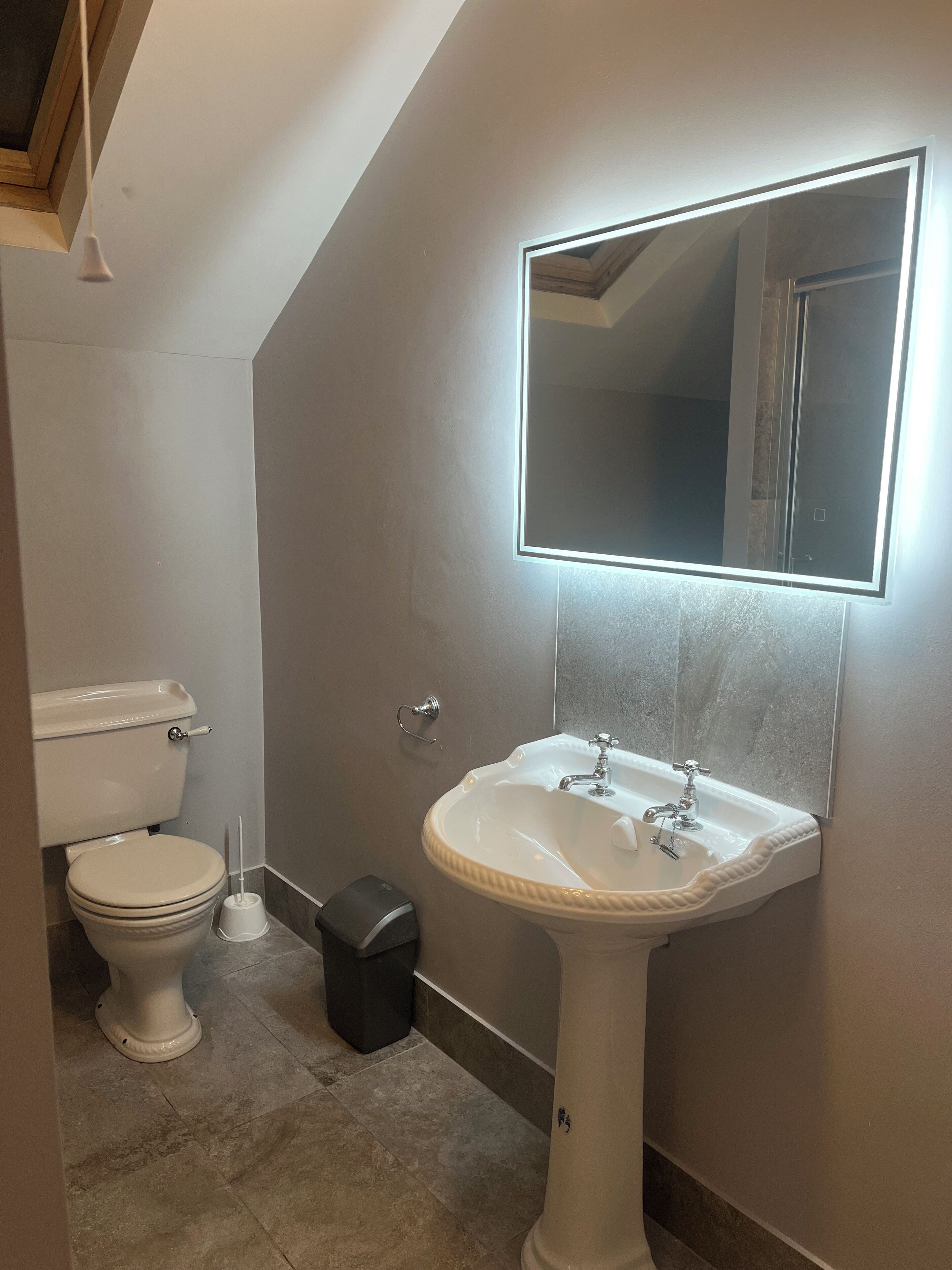 Une petite salle de bain avec des toilettes, un lavabo et un miroir.
