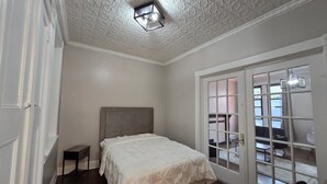 Ein Schlafzimmer mit einem Bett, einem Nachttisch, einer Tür mit Blick auf einen Außenbereich und einer strukturierten Decke.