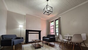 Ein Wohnzimmer mit Kamin, zwei Sofas, einem Couchtisch und einem Essbereich mit Stühlen.