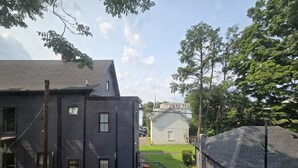 Ein Wohngebiet mit einem zweigeschossigen Haus, einem kleineren Anbau und einem umzäunten Garten mit Terrasse.