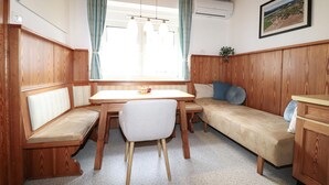 A cozy room with a wooden bench, a small table, a sofa, and a window with curtains. - Lovely apartment in Strau with WiFi (Strau)