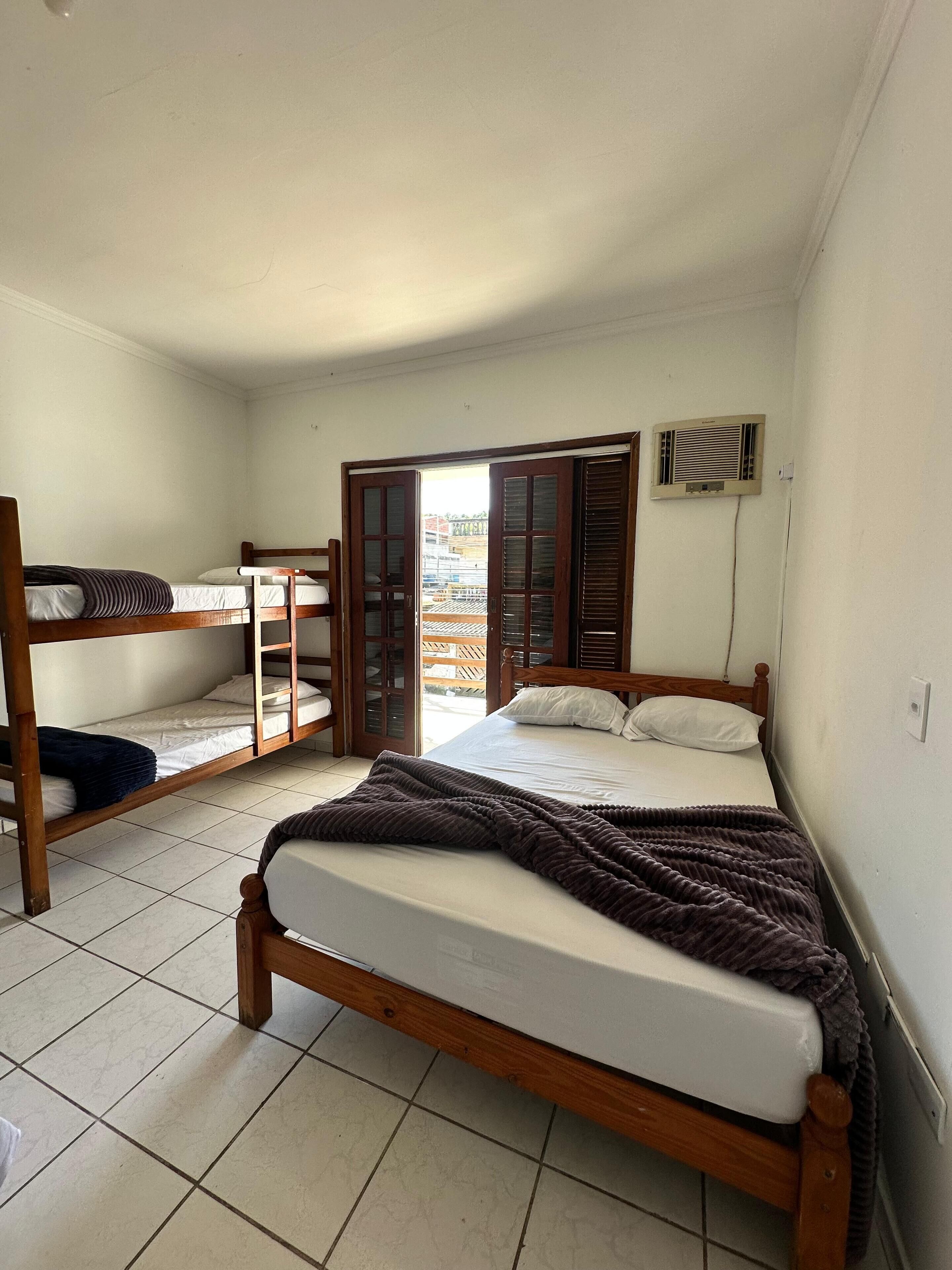 A dormitory room with a single bed, a bunk bed, and a desk.
