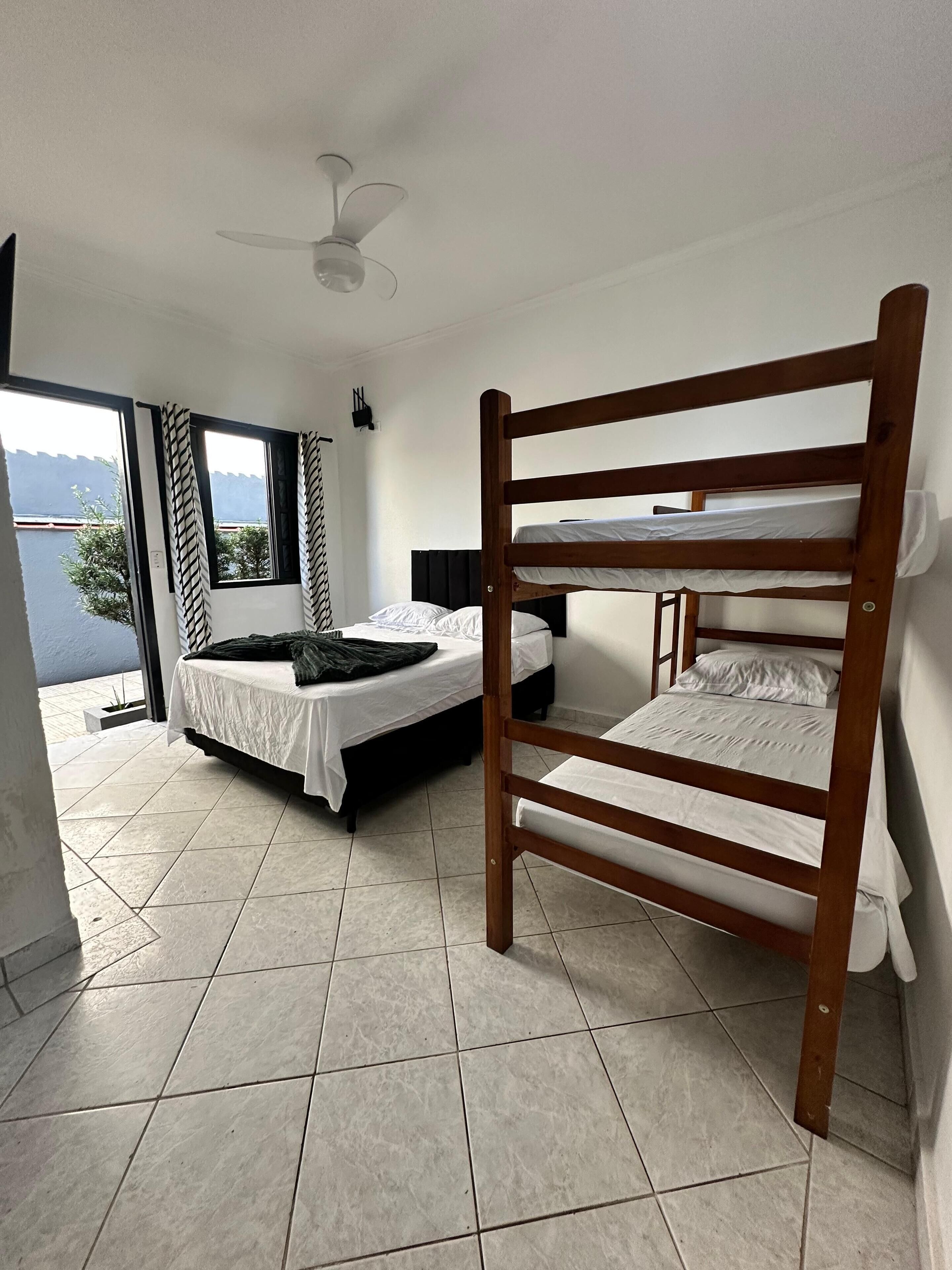 A room with a bunk bed, a single bed, and a ceiling fan.