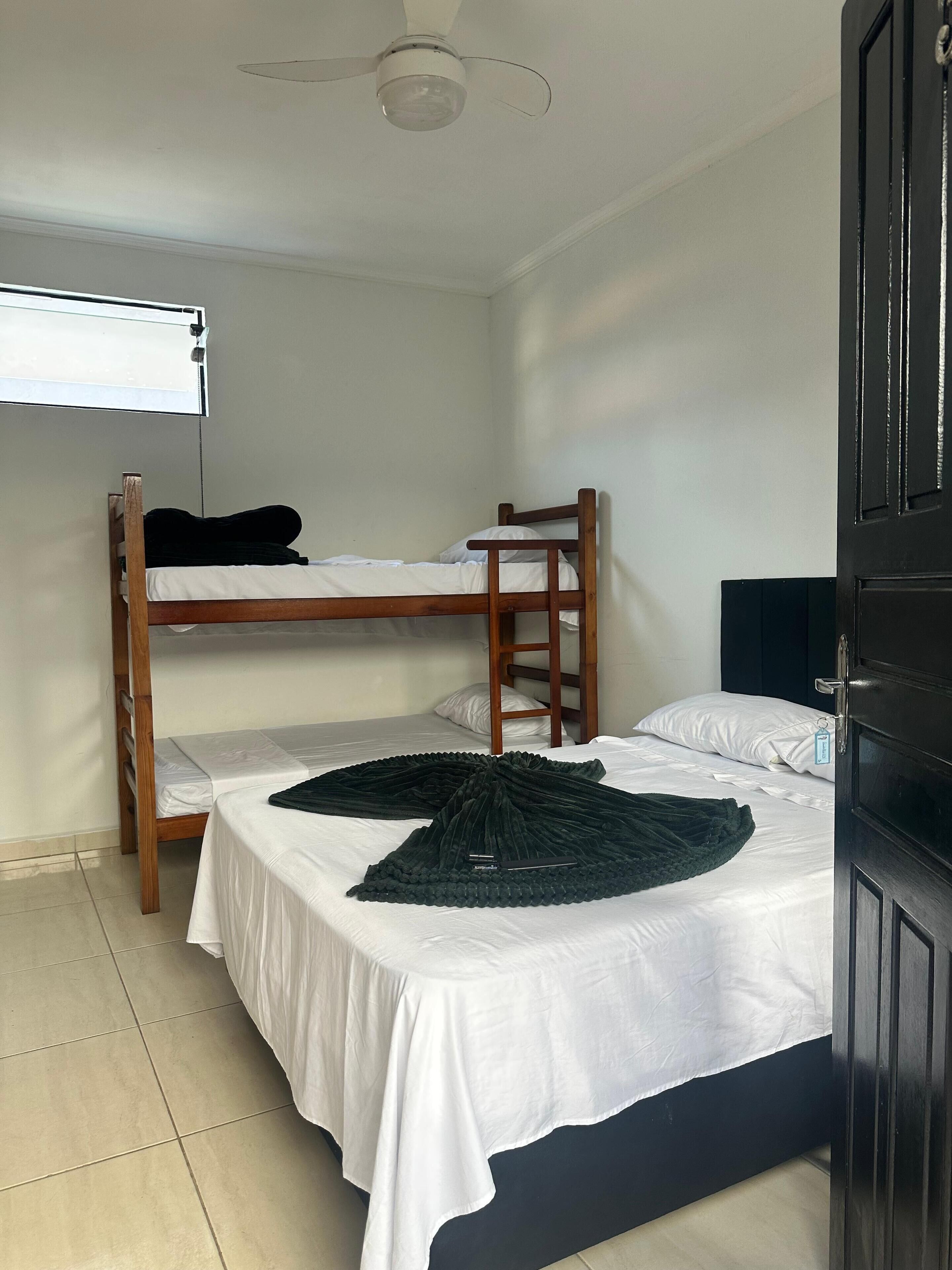 A room with a bunk bed, a desk, and a ceiling fan.