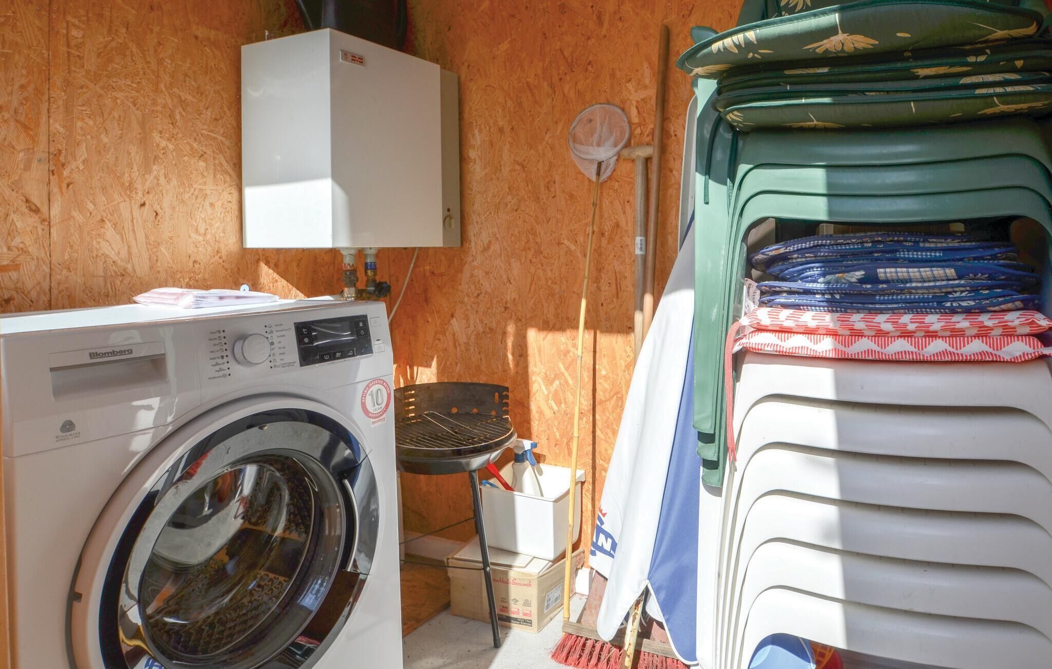 A compact laundry area with a front-loading washing machine, a stacked drying rack, and a small table with cleaning supplies.