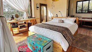 A spacious tented room with a large bed, a wooden desk, a hanging lamp, and a view of the outdoors. - Sironka Cabin Getaway in Ole Lekurruki, Naromoru. (Mureru Farm)