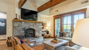 A cozy living room with a stone fireplace, leather sofas, and a large window. - Stunning, Remodeled Mountain Retreat in Mammoth Lakes! (Mammoth Lakes)