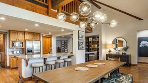 A spacious kitchen with wooden cabinets, a stainless steel refrigerator, and a central island with stools. - Stunning, Remodeled Mountain Retreat in Mammoth Lakes! (Mammoth Lakes)