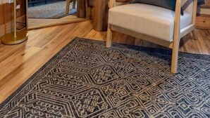 Um quarto acolhedor com paredes de madeira, uma mesa redonda com cadeiras, um espelho grande e uma janela com persianas.