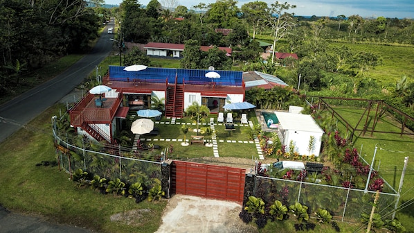 A residential property with a fenced yard, a swimming pool, and a red-roofed building.