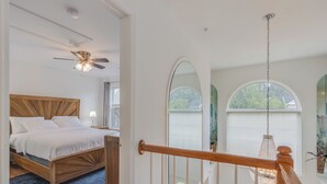 Une chambre à coucher avec un lit en bois, un ventilateur de plafond et une vue sur l’extérieur par une fenêtre.
