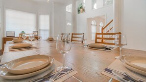 Un coin repas avec une table en bois mise pour le repas, comprenant des assiettes, des couverts et des verres à vin.