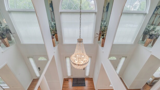 Un intérieur spacieux agrémenté d’un grand lustre, de parquets en bois et de nombreuses fenêtres.