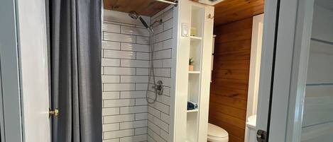 Un bagno con doccia, wc e pavimento in legno.