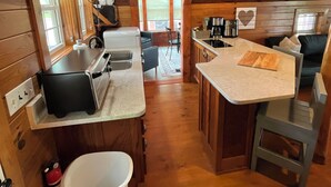 A cozy cabin-style kitchen with wooden walls, a central island, and a view of the outdoors.