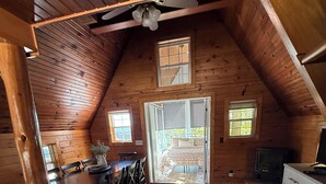 A cozy wooden cabin interior with a dining area, a bed, and a television.