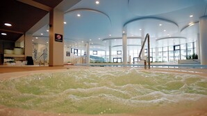A hot tub area with a pool, indoor seating, and a no smoking sign.