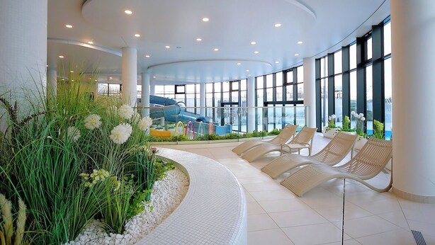 A modern indoor area with a curved ceiling, seating area with chairs, and a view of a water slide.