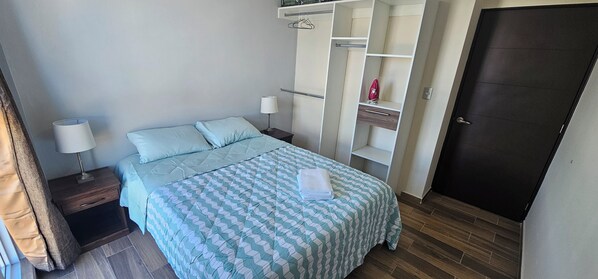 Une chambre à coucher avec un lit, des tables de chevet, une armoire et une porte.