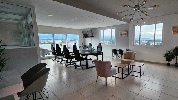 Une salle de réunion spacieuse, dotée d’une grande table et de chaises, d’un téléviseur et de grandes fenêtres offrant une vue sur la ville.