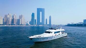 A white yacht on calm waters with a city skyline in the background.