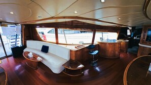 A luxurious interior with a white sofa, wooden tables, and a bar area. - Riviera Leisure Yachts Dubai  (Dubai)