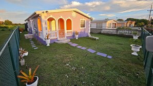 A house with a front porch, a small garden, and a paved walkway leading to the entrance.