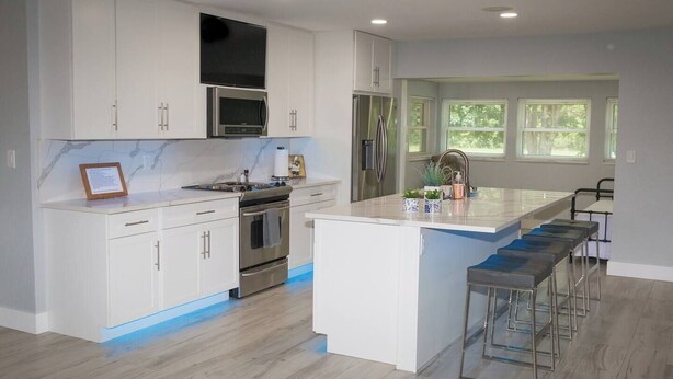 A modern kitchen with white cabinetry, stainless steel appliances, and a central island with bar stools.
