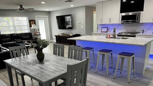 A modern kitchen with a central island, bar stools, and a dining area with a table and chairs.