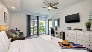 Een hotelkamer met een bed, een bureau, een stoel, een televisie en een balkon met uitzicht.