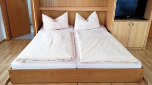 A double bed with a wooden frame, two pillows, and a television on a stand in the corner. - Studio 'Typ A 19' with Shared Garden, Balcony and Wi-Fi (Immenstaad am Bodensee)
