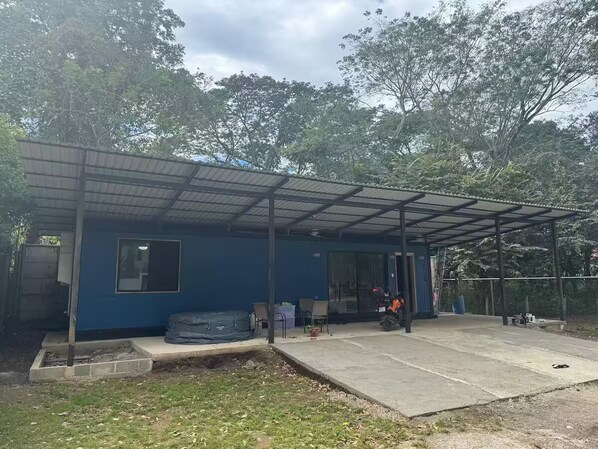 A blue building with a covered patio area, a motorcycle, and a fenced outdoor space. - Beautiful Casa Azul (Potrero)