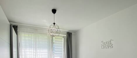 A modern bedroom with a bed, bedside table, and a geometric pendant light.