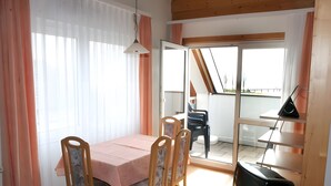 A dining area with a table and chairs, a television, and a view of the outside. - Sommerhof Rauber - Apartment 'Type B 24' with Lake View, Shared Garden & Wi-Fi (Immenstaad am Bodensee)