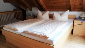 A wooden bed with two pillows and a nightstand with a lamp.