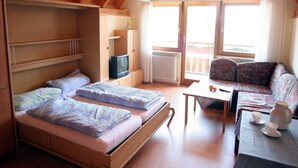 Una habitación acogedora con una cama, un sofá, una mesa con tazas y un hervidor, y un televisor.