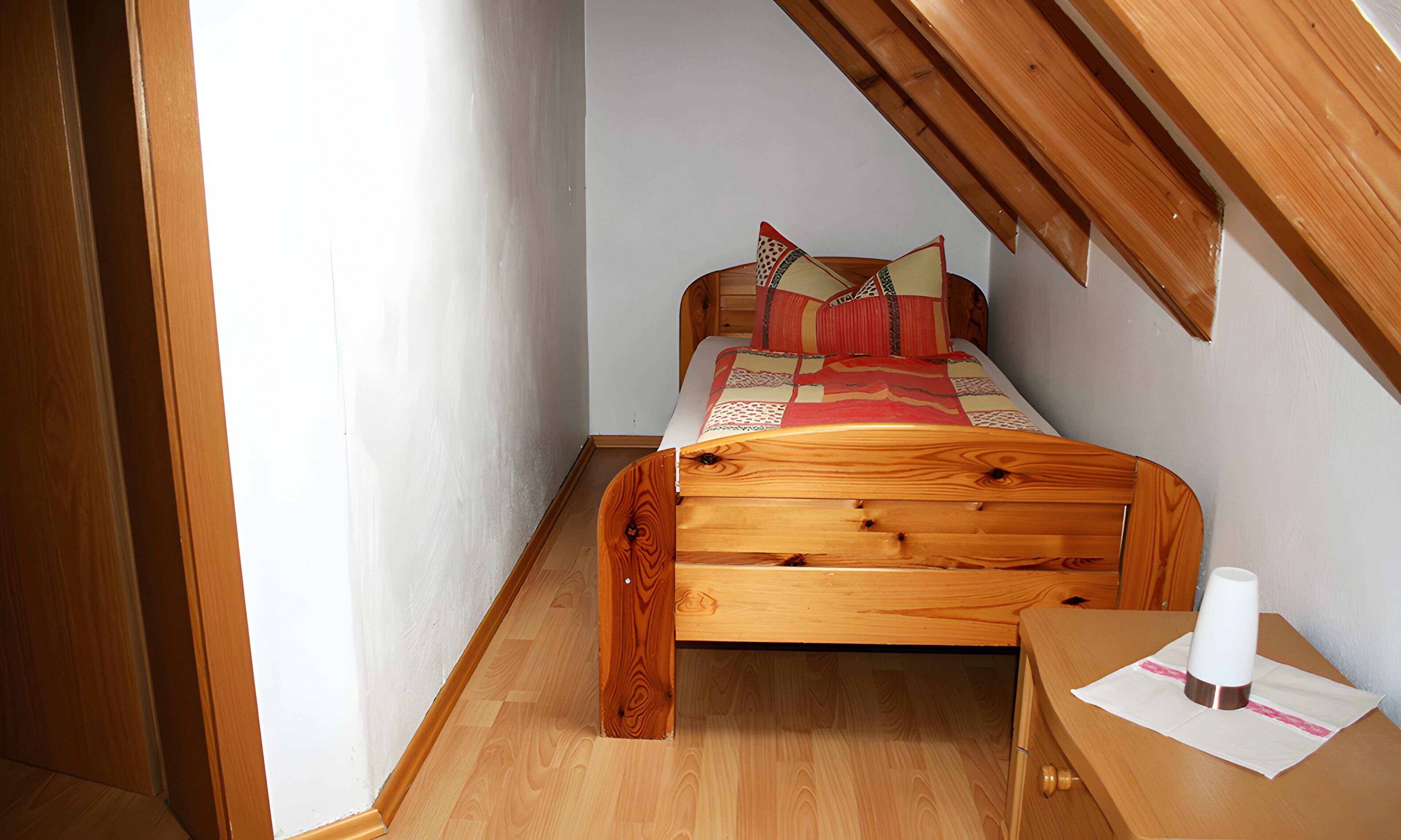 Un dormitorio con cama de madera, mesita de noche y ventana.