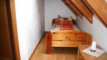 Un dormitorio con cama de madera, mesita de noche y ventana.