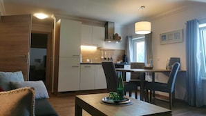 A compact living space with a kitchenette, a dining area, and a seating area with a sofa and a table.