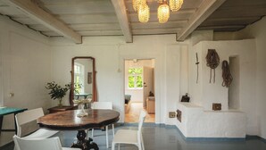 Un coin repas avec une table ronde, des chaises blanches, un miroir et un lustre.
