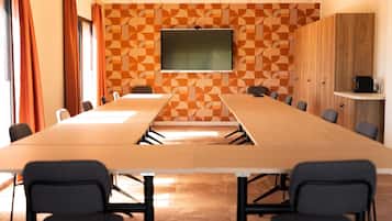 A conference room with a long table, chairs, a television, and a patterned wall.