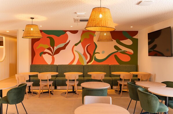 A modern interior with a green sofa, round tables, and hanging lamps. - Best Western Terra Alta Perpignan Aeroport (Perpignan)