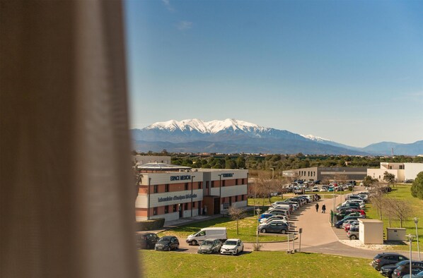 A parking lot with cars, a building labeled 'ERNIE MEDICAL,' and snow-capped mountains in the background.